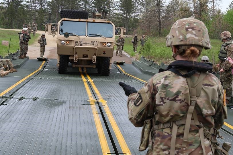 Soldiers ground guiding HEMTT over bridge